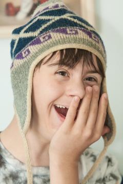 Happy teen wearing warm hat with his hand over his mouth