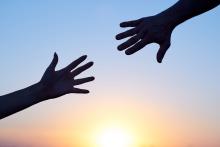 Silhouette of two hands reaching towards each other