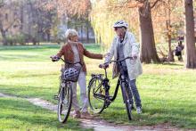 Two people walking bikes in the park