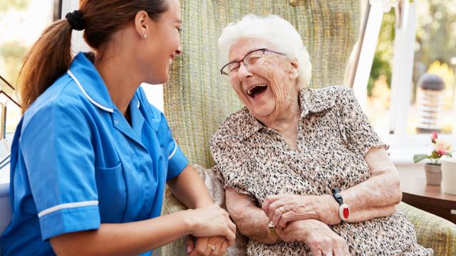 Older adult laughing with caregiver