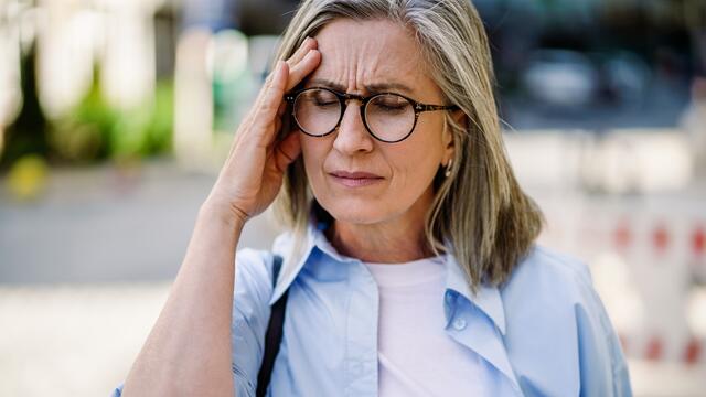 Adult with headache has a pained expression and hand on temple