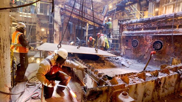 A welding team works on the interior of a ship