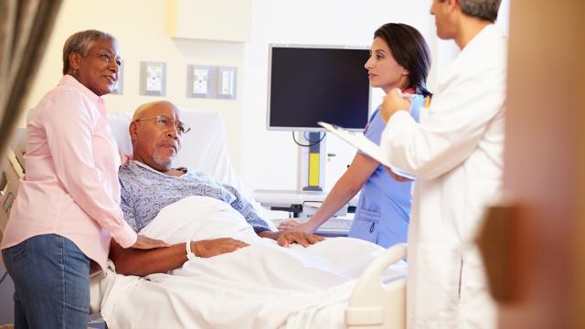 Two doctors treat an elderly in the hospital who is accompanied by a partner