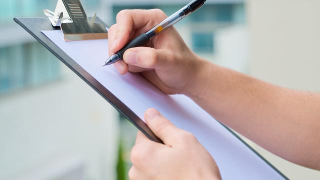 Close up of hands holding a clipboard with a pen