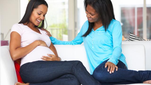 Pregnant person with her friend sitting in the living room