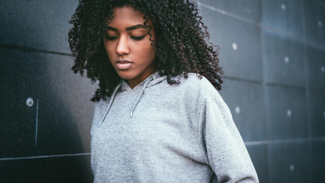 Reflective teen standing next to a wall