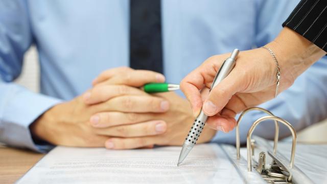 Two people looking at a binder, one writing a note