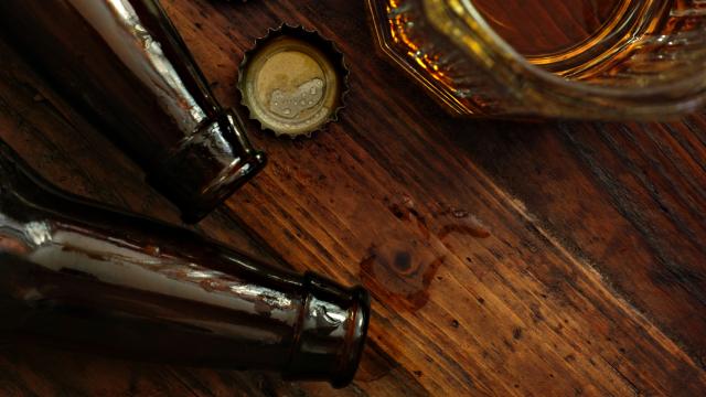 Close up of long-neck beer bottles, bottle caps and a partial glass of beer,