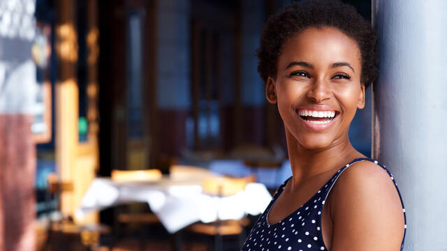 Happy young adult standing against the wall