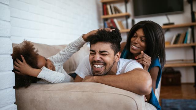 Two laughing adults and child on a sofa