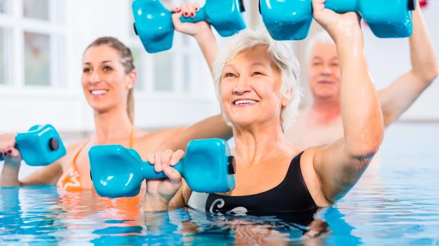 Three adults exercising with dumbbells in a swimming pool.