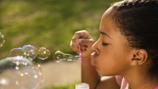 Young child blowing bubbles outside