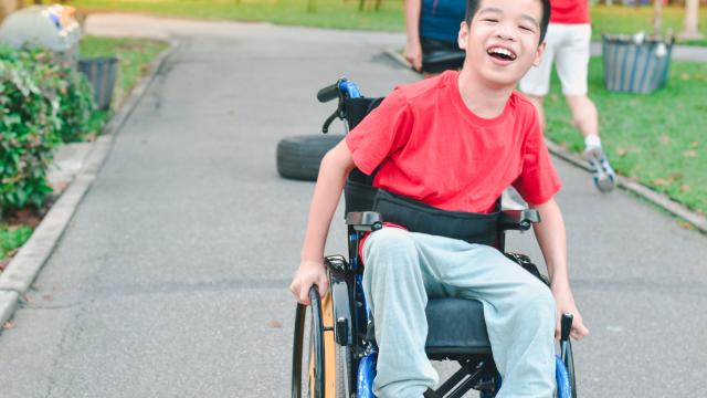 Smiling child in wheelchair on sidewalk