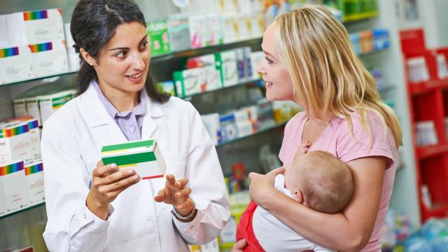 A pharmacist talks with an adult with a baby.