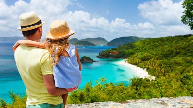 Adult and child enjoying a tropical beach view from a parapet