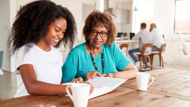 Teen and older adult sitting at a counter looking through a photo album