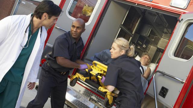 Two EMTs delivering a patient to hospital with a doctor in white coat looking on