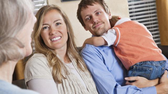 A couple with a child talk to someone in a therapy/clinical setting.