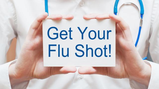 Medical staff's hands holding a sign saying get your flu shot!