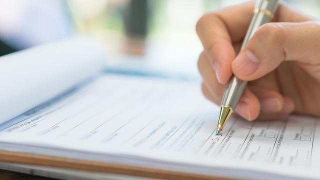 Hand holding a pen completing an application.