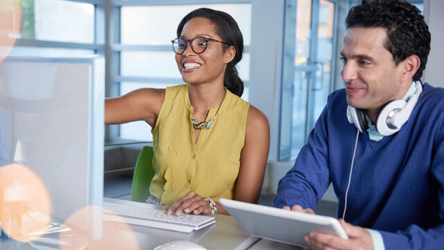 Two coworkers with a tablet and a desktop computer