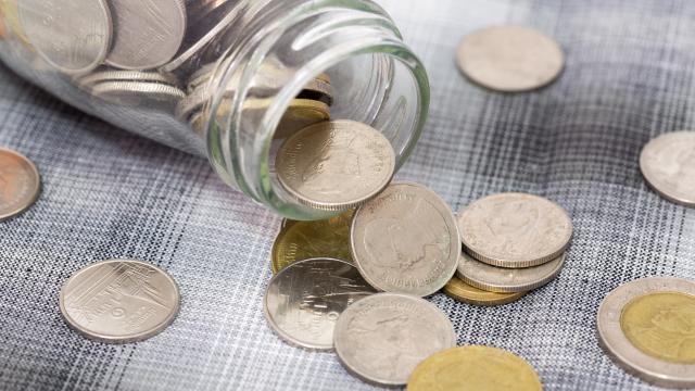 A glass bottle spills with coins inside.