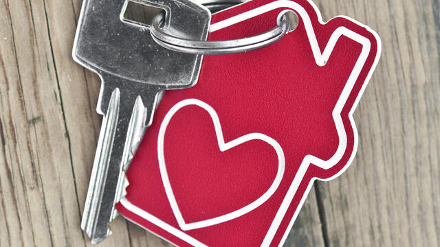 A red house tag with a heart with a key attached to it.