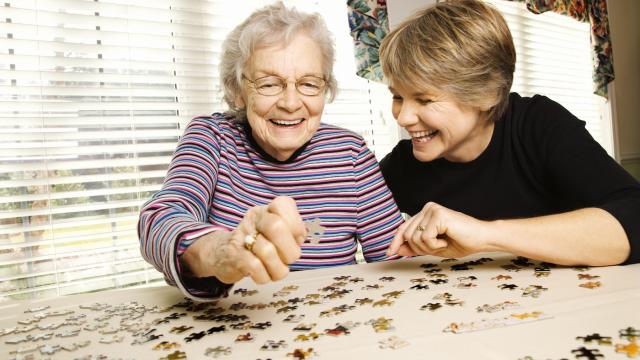 Elderly person and younger person do a puzzle together at home