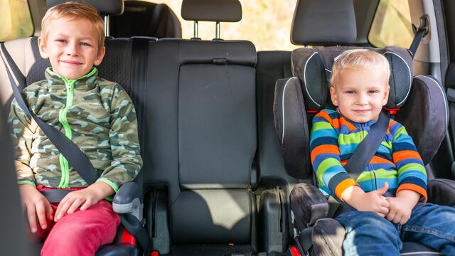 Two toddlers in car seats in the back of a vehicle