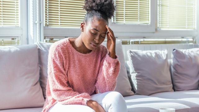 Person with headache sitting on a sofa