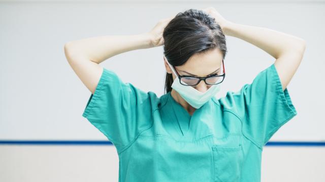 A medical professional tying on a surgical mask.