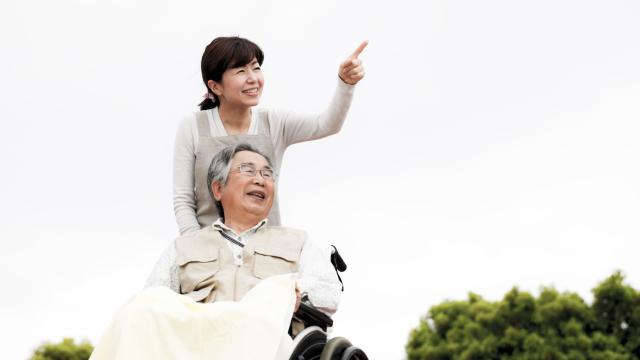 A person standing by an adult in a wheelchair pointing to something