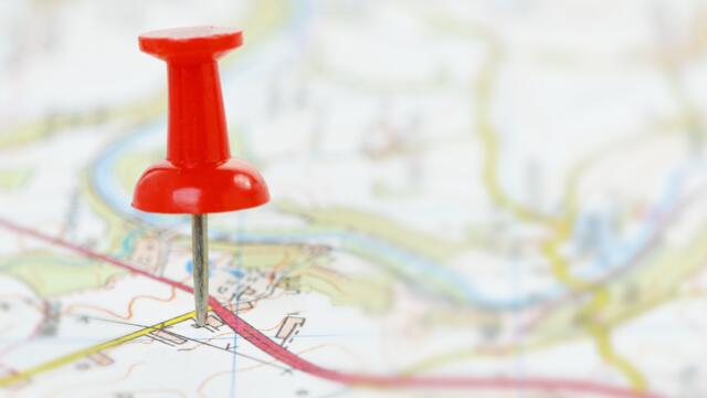 A red push pin marked travel destination on a map