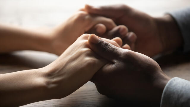 Close up of two people clasping hands