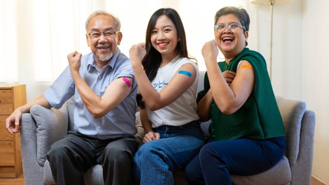 Three smiling people showing vaccinated arms