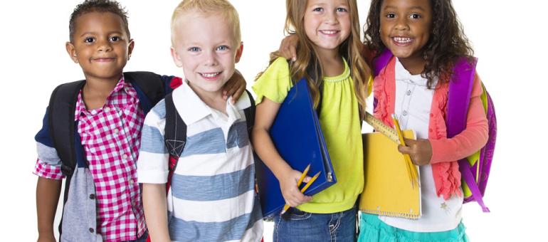 Young children wearing backpacks and school clothes smiling against white background
