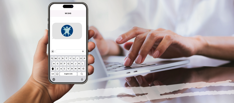 Hand holding a cell phone in front of hand typing on a keyboard