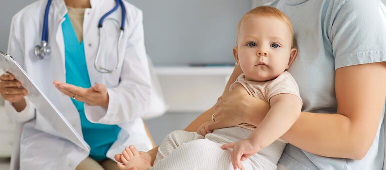 Doctor talks with adult holding a baby