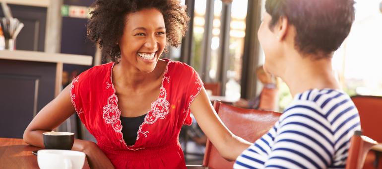 Two adults enjoying chatting at a cafe.