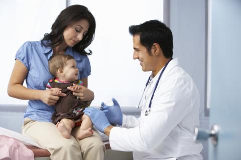 An adult holds her baby while the doctor gives her a vaccination