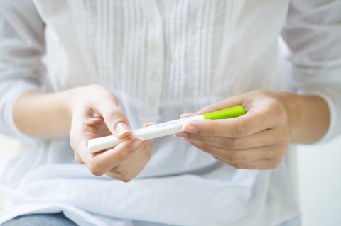 A pregnancy test holding by a pair of hands.
