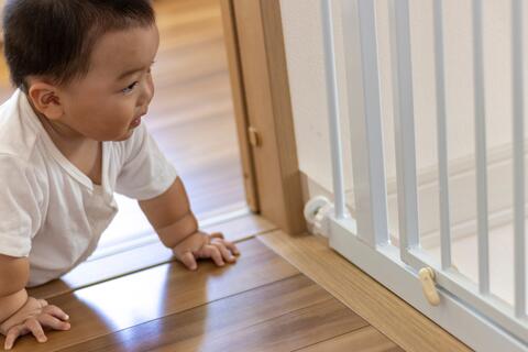 Baby crawling towards steps with a closed baby gate