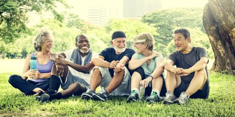 Group of older adults relaxing on the grass after workout