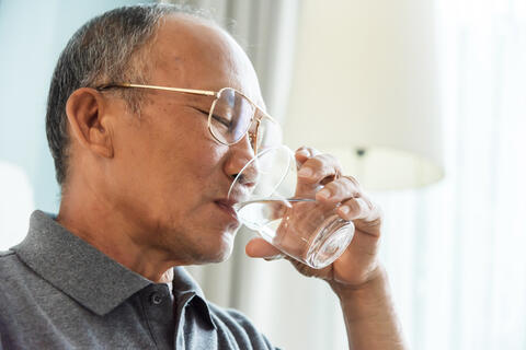 Close up of an adult drinking a glass of water
