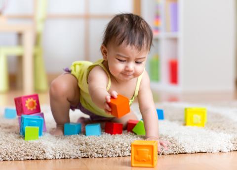 A toddler playing with blocks on an area rug at home