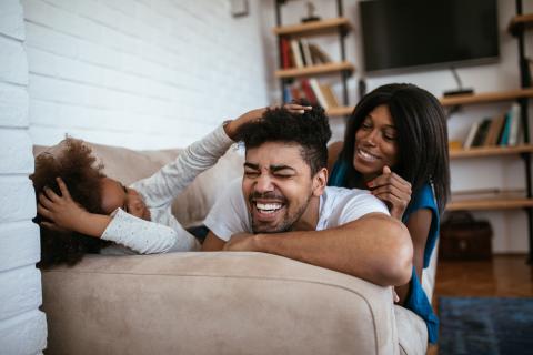 Two laughing adults and child on a sofa