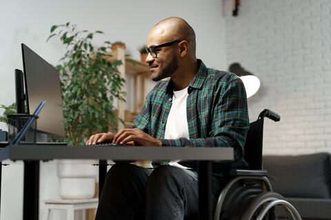 Adult sitting in a wheelchair using a laptop