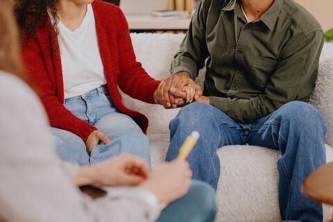 Close up of a couple holding hands while at a therapist appointment