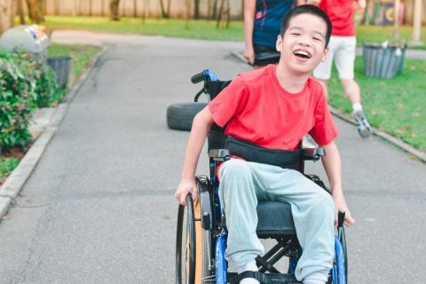 Smiling child in wheelchair on sidewalk
