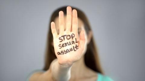 Adult person with hand in front of face with Stop Sexual Assault written on it.